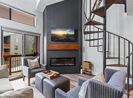 Living area with a fireplace and spiral staircase in Snowcrest 302.