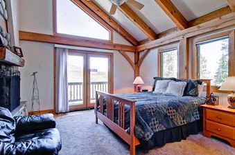 The primary bedroom at Snow Mountain Lodge features exposed timber and a view.