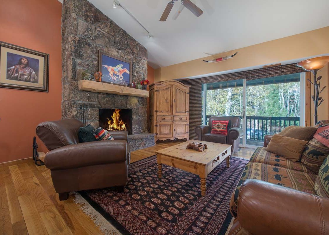 A cozy living room in Whiteridge B3 featuring a stone fireplace and leather furniture.
