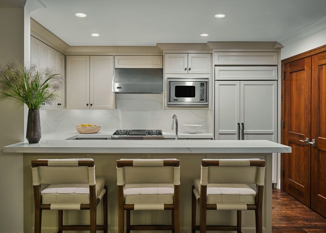A modern kitchen with light colored cabinets and white countertops.