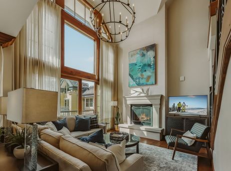 A luxurious living room in Eagles Nest at the Ritz-Carlton features a stone fireplace, plush seating, and large windows.