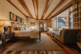 A luxurious master bedroom with a king-sized bed, wooden beams, mountain views, and elegant decor at San Sophia Vista at See Forever.