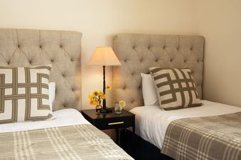 A close-up view of twin beds with tufted headboards and a shared nightstand at Granite Ridge Lodge 17.