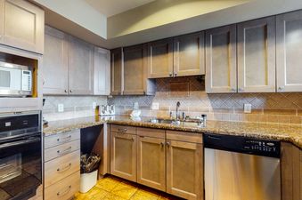 The kitchen in Meadows Clarion 2 has stainless steel appliances, a double sink, granite countertops, and wood cabinets.
