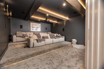 A luxurious home cinema in Powder Day Chalet with plush sofas, dark walls, and subtle lighting, creating an ideal movie-watching experience.