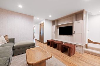 A luxurious entertainment space at Village Hall 13, featuring a large screen TV, plush seating, and warm lighting.