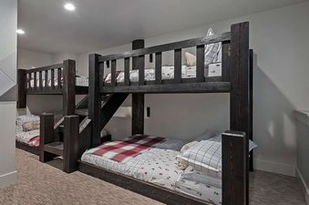 A cozy bedroom featuring sturdy wooden bunk beds with checkered and patterned bedding.