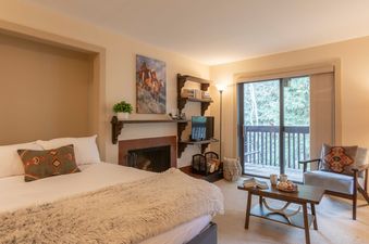 A cozy studio bedroom in Sleeping Indian W12 with a fireplace, private balcony, and seating area.