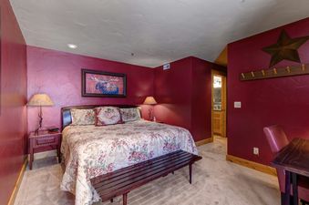 The bedroom at Deer Valley Delight features a king size bed, a wooden bench at the foot of the bed, and a nightstand next to the bed.