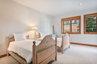 A bedroom with two twin beds and a lamp on a nightstand between them.
