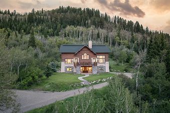 Exterior view of Starfall Summit cabin surrounded by dense green forest at sunset.