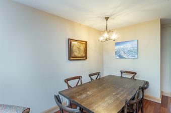 The dining area in Cimarron Lodge 35 features a rustic wooden table with six chairs, an antler chandelier, and wall art including a framed map and a ski resort poster.