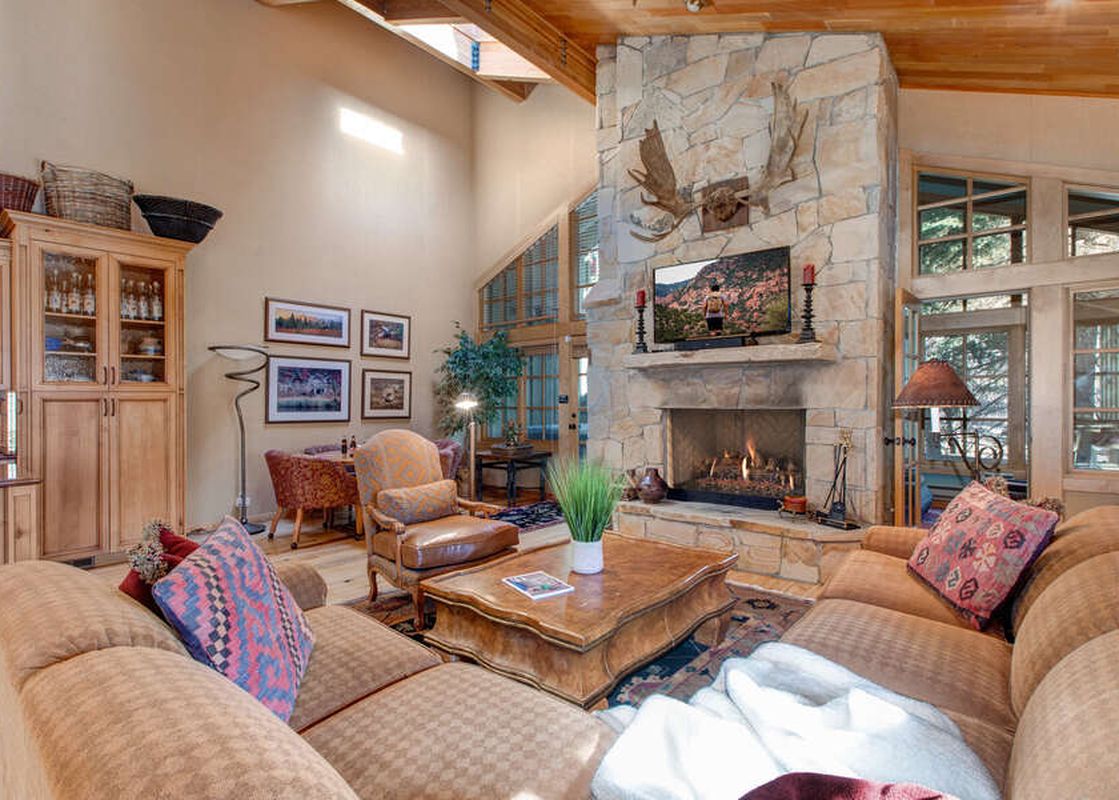 Spacious living room with a stone fireplace, large windows, and comfortable furniture.