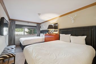 Two bedrooms with a large bed in one room and a smaller bed in the other room