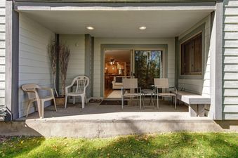 The patio of Snow Flower 132 Park City features comfortable seating, a small table, decorative branches, and access to the interior through sliding glass doors.
