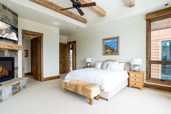 The master bedroom at 30 Spur Road Moonlight Basin features a king-sized bed with a plush headboard and a cozy sitting area.