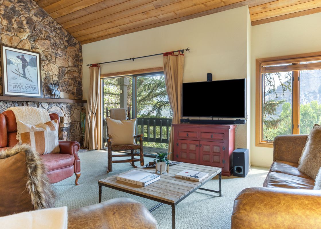 A cozy living room at 88 Ridge Point features a stone fireplace, comfortable leather seating, and large windows offering scenic outdoor views.