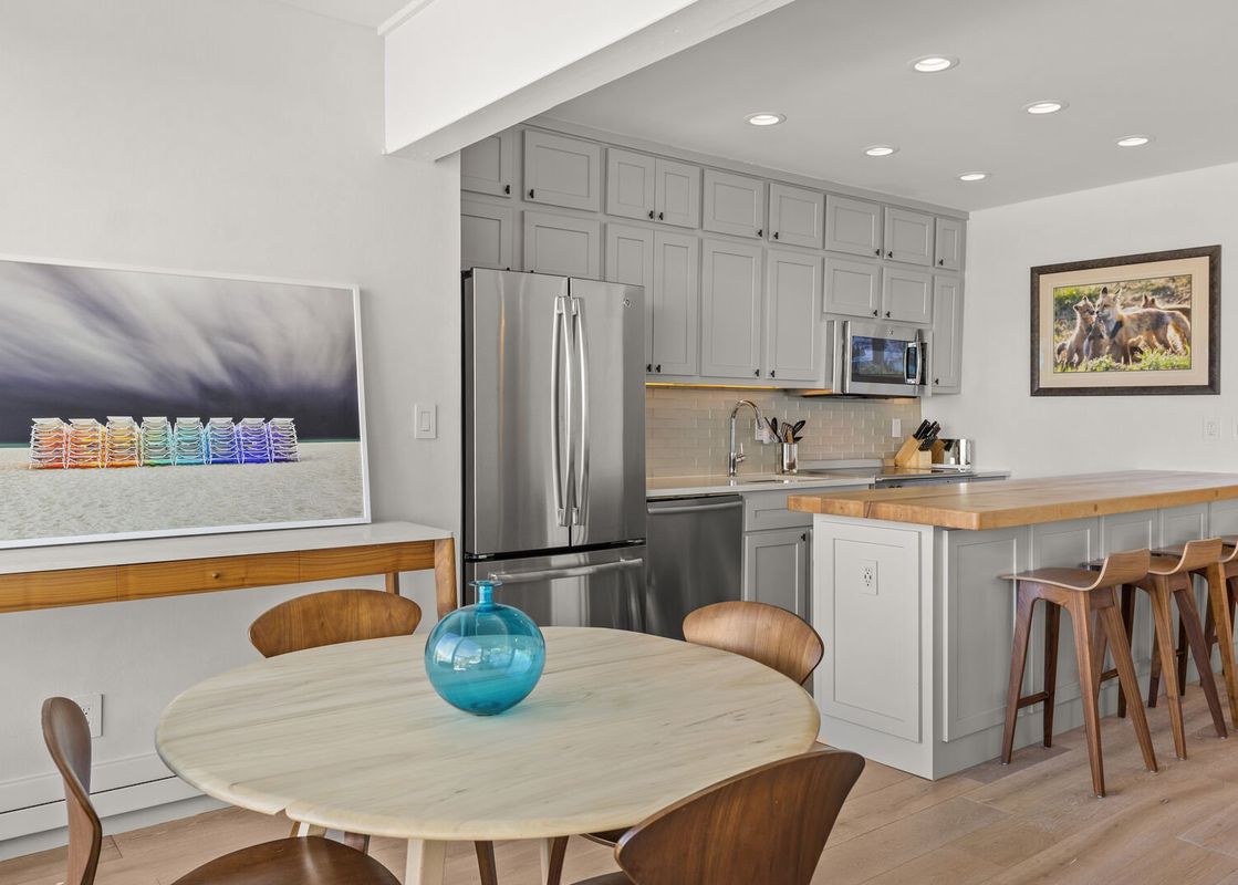 The kitchen of Durant Condominiums Unit D4 features stainless steel appliances, grey cabinetry, and a breakfast bar with seating.