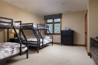 Bunk room with two dark metal bunk beds, black dressers, a TV, and a window with mountain views at Flat Tops Peak Penthouse One Steamboat Place 701.