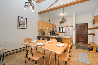 The image features the fully equipped kitchen and inviting dining area of Beaver Village 833, highlighting the natural wood accents and modern design of the open-concept space.
