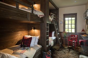 Cozy rustic bunk room with dark wood built-in beds and flannel pillows.