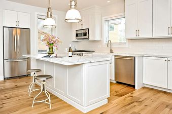 The kitchen of Boulders Way 126 has white cabinets, stainless steel appliances, and a large island with a white countertop and a breakfast bar.