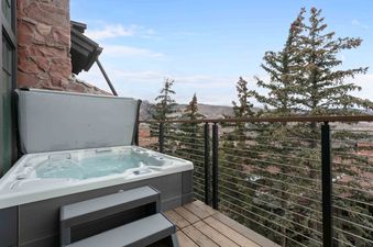 A private hot tub on a deck with mountain views, featuring bubbling water, a partially open gray cover, and a modern design.