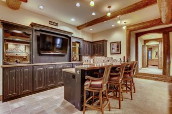 The Ski Hi Lodge features a cozy bar area with dark wood cabinetry, a large flat-screen TV, and leather bar stools, perfect for entertaining.