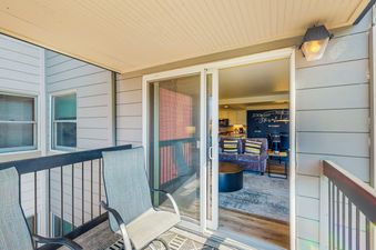Balcony view from Torian Plum Plaza 605 showing comfortable seating and an open sliding glass door into the living area.