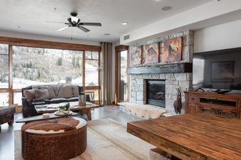The living room of 132 Two Bedroom Black Diamond Lodge features a large leather sofa, a stone fireplace, and a flat-screen television.