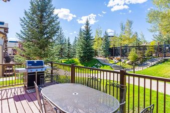 Private deck at EagleRidge Townhomes 1510 featuring a BBQ grill and patio dining table with views of landscaped grounds.
