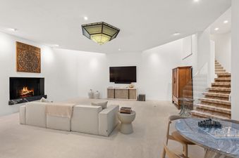 A modern and bright lounge area features a large neutral sofa facing a fireplace with a TV above the media console, all under a unique Morrocan-style ceiling light.