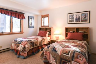 A cozy bedroom with two twin beds featuring rustic patchwork quilts in Windriver 1.