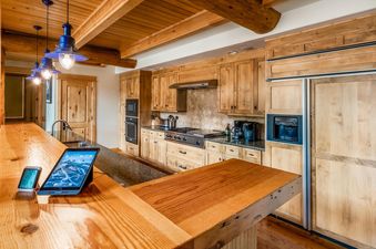 The kitchen in Moonlight Basin Penthouse 3 features a breakfast bar, wooden cabinets, stainless steel appliances, and a large fridge.