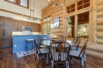 The dining area at Wild Cat Lair features a wooden table and chairs with a view of the outdoors.