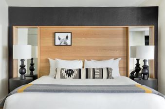 Modern king bed with light oak headboard and geometric accent pillow in the Gravity Haus JH Deluxe King room.