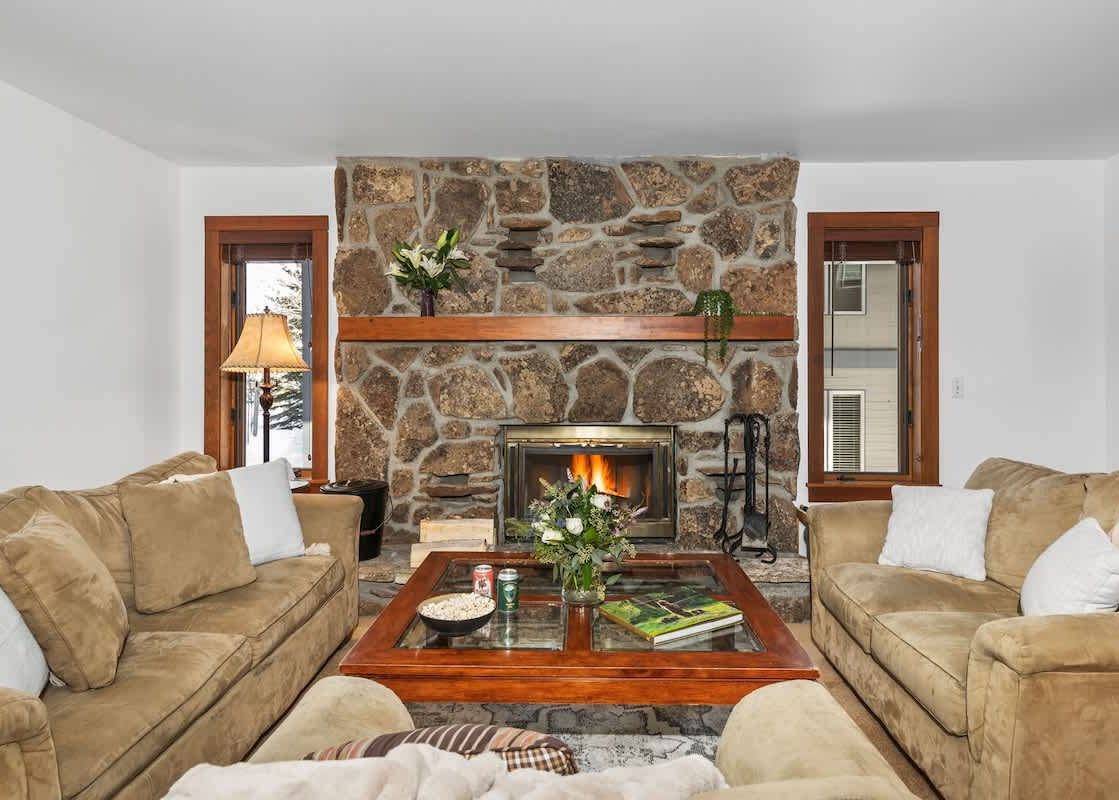 A cozy living room at Sundance Jackson Hole featuring a stone fireplace and plush seating.