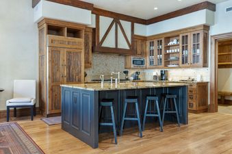 A modern kitchen with wooden cabinets and a large island with bar stools.