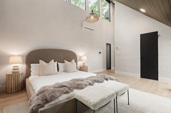 A serene bedroom at Onyx Lodge with a king-sized bed, unique wooden bedside tables, and a modern design.