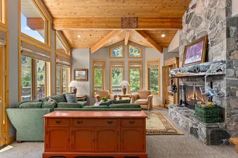 The living room in Trails End Lodge 18 features a large, comfortable sofa, a stone fireplace, and a wooden cabinet.