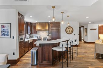 Modern open-concept kitchen at Arrowleaf 209 featuring wood cabinetry and a breakfast bar with three stools.