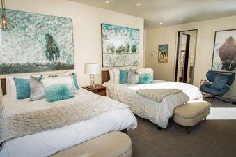 Two beds with fluffy pillows and a beige faux fur throw in a light and airy bedroom in White Pine Canyon.