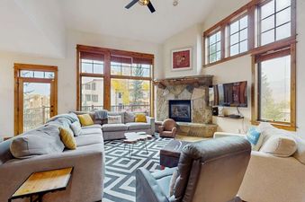 Living room of EagleRidge Townhomes 1455 with a stone fireplace, large sectional sofa, and floor-to-ceiling windows.