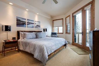 A cozy bedroom with a king-size bed, modern decor, and a private balcony at Chateau Chamonix CX311.