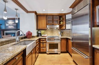 A modern kitchen with wood cabinets, granite countertops, and stainless steel appliances.