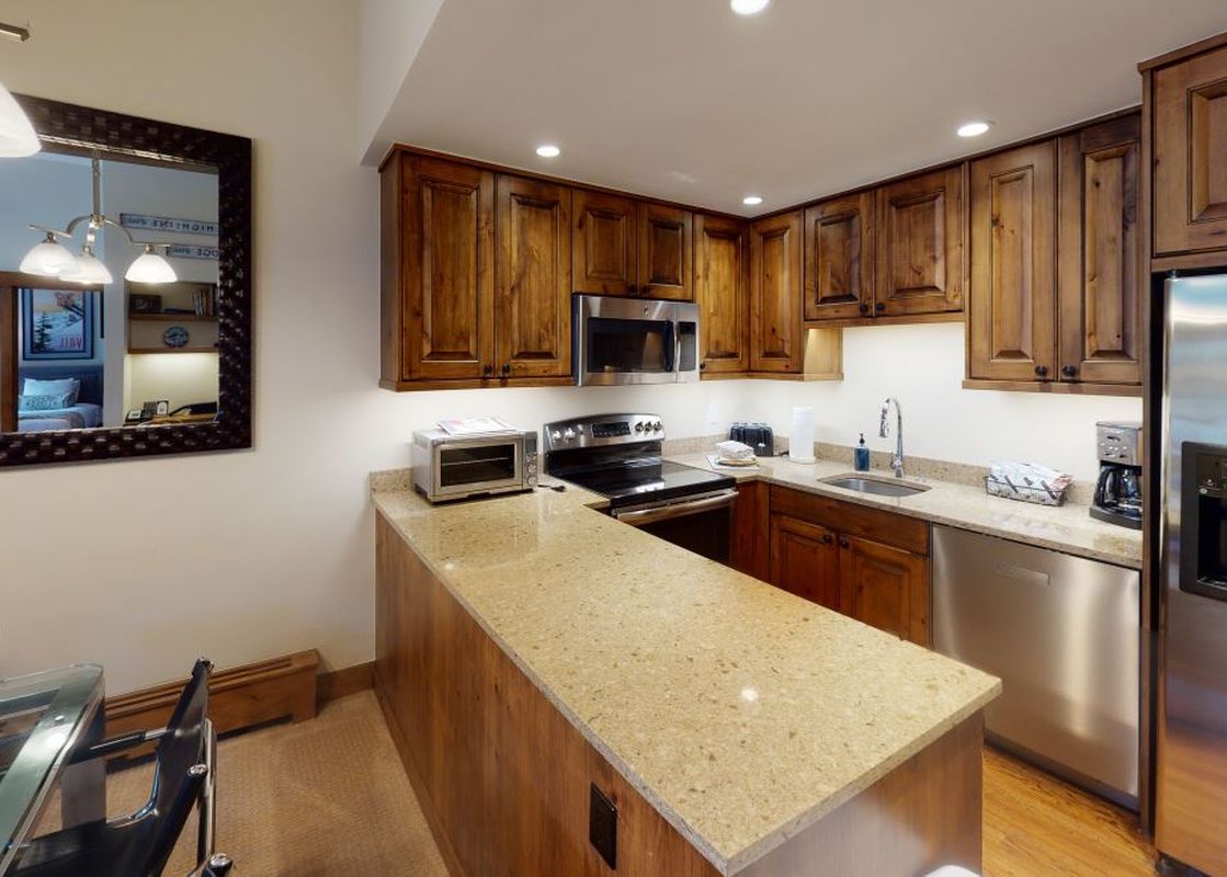The kitchen in Manor Vail 212 has stainless steel appliances and wood cabinets.