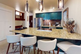 A kitchen with a granite countertop and four bar stools.