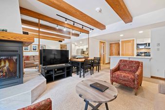 A living room with a fireplace, a couch, a TV, and a dining table.