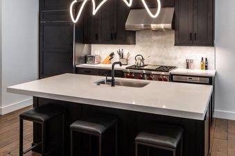Moonlight Basin 9 Wildwood features a modern kitchen with a large island with seating, stainless steel appliances, and sleek black cabinetry.