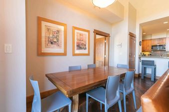 A dining table with chairs and a couch in a well-lit living space.